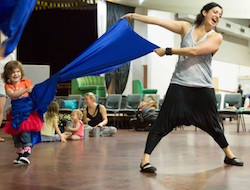 Murmuration-facilitators-children-participating-in-Mini-Murmurs-class-dancing-with-strips-of-blue-fabric-smiling-and-happy Murmuration-facilitators-children-participating-in-Mini-Murmurs-class-dancing-with-strips-of-blue-fabric-smiling-and-happy